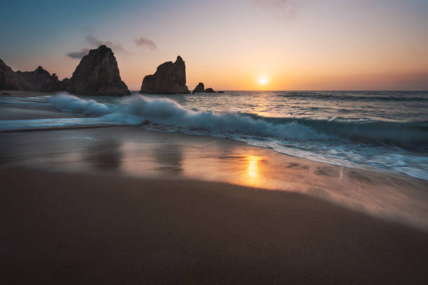 istock Portugal Ursa Beach at atlantic coast. Sunset reflection. White wave roll towards sandy beach with rock silhouette in background. Picturesque landscape panorama 1177918612
