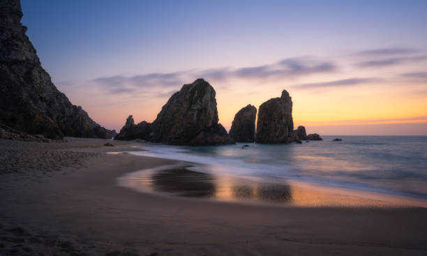 istock Epic Ursa Beach with rock silhouette and reflection against golden sunset light. Cabo da Roca, Sintra at Atlantic Ocean coast in Portugal 1177918662