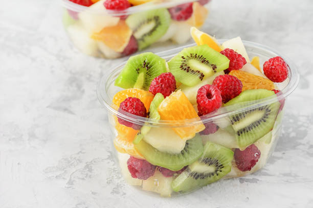 bayas de frutas tropicales rebanadas frescas en recipiente. deliciosa bocadillo saludable listo para comer ensalada en el primer plano de la copa transparente vista elevada. comida vegetariana cruda. cítricos, kiwi, frambuesas para el almuerzo - fruit cup fotografías e imágenes de stock