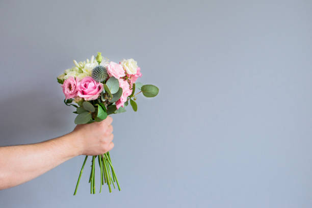 mano con un mazzo di fiori. - surrounding wall holidays and celebrations nature wall foto e immagini stock