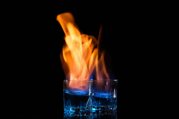 istock Close up, macro.Two glasses with cocktails, the surface of which burns with a bright flame. Black background. Copy space. 1177940047
