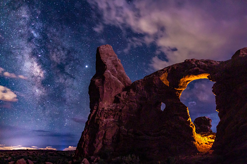 Two light sources on Turret Arch: one manmade, one mother nature, Lightning, light up Turret Arch in Arches National Park, Utah.