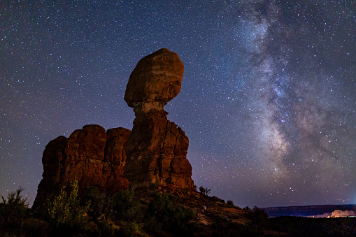Iconic Balanced Rock silhouetted against a star-filled Milky Way in Arches National Park in Moab, Utah.
