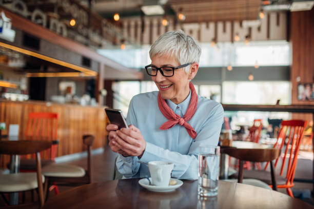 istock Beautiful mature woman using mobile phone at coffee shop 1177943005
