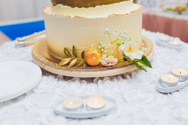 istock Three-tiered white wedding cake decorated with flowers from mastic on a white wooden table. Picture for a menu or a confectionery catalog with copy space. 1177943234