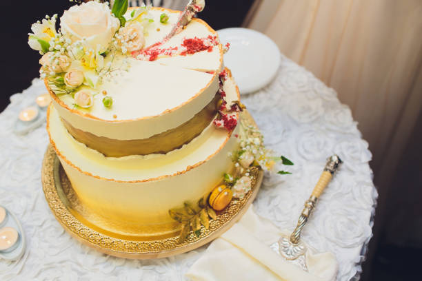 istock Three-tiered white wedding cake decorated with flowers from mastic on a white wooden table. Picture for a menu or a confectionery catalog with copy space. 1177943243
