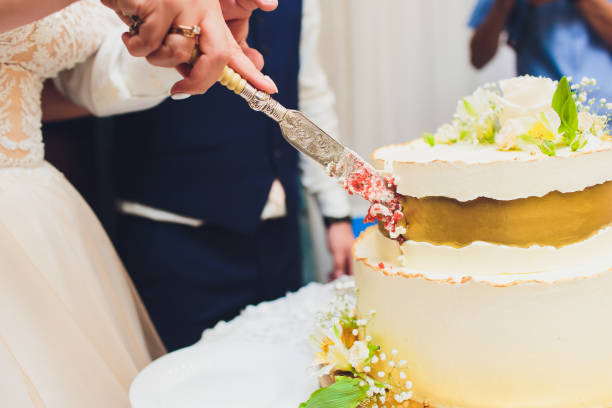 istock Three-tiered white wedding cake decorated with flowers from mastic on a white wooden table. Picture for a menu or a confectionery catalog with copy space. 1177943244