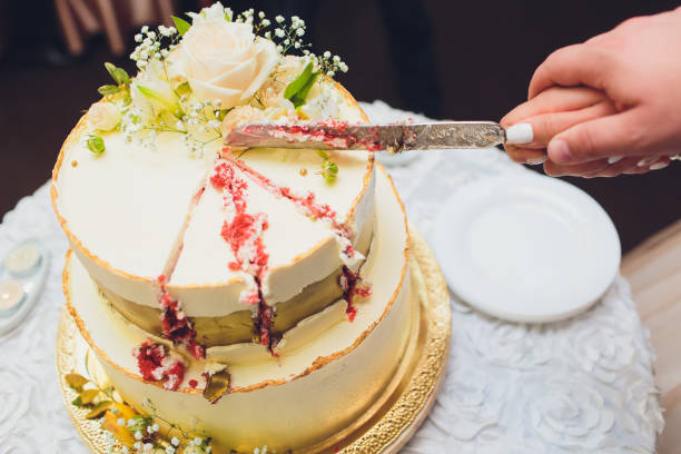 istock Three-tiered white wedding cake decorated with flowers from mastic on a white wooden table. Picture for a menu or a confectionery catalog with copy space. 1177943247