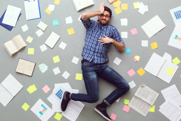 istock Young man isolated on grey background with papers and notes sleepy 1177944452