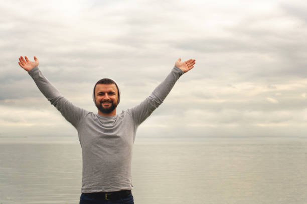 istock A young man stands ashore facing the camera. There is a gray hat on his head. Traveler. 1177944534