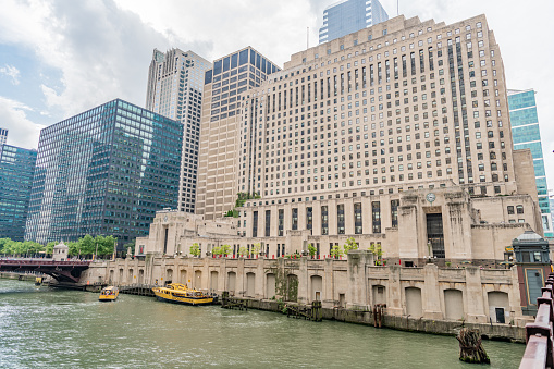 Chicago, IL / USA - September 11, 2019: Famous yellow water taxis pull in to dock by the iconic Merchandise Mart building, downtown, in the Loop. Water taxis run daily along the Chicago River.