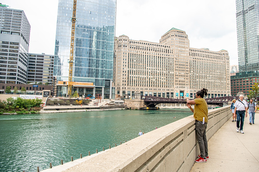 Chicago, IL / USA - September 11, 2019:  A man stops to take a photo of the beautiful scenery downtown, in the Loop. Chicago is a very scenic city with much historic architecture.