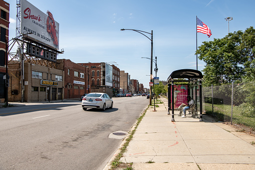 Chicago, IL - September 7. 2019: Street scene in the West Loop and West Town neighborhoods, downtown Chicago. People wait for a bus as traffic passes on a busy street.