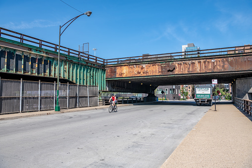 Chicago, IL - September 7. 2019:  A young man rides a bicycle in the Fulton Market, West Loop area downtown, a very industrial area that is currently being revitalized.