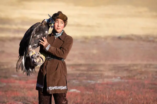 Traditional kazakh eagle huntress petting her golden eagle that is used to hunt for fox and rabbit fur. Ulgii, Western Mongolia.