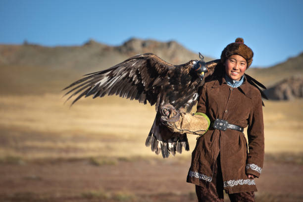 Young kazakh eagle hunter with his golden eagle. Traditional kazakh eagle hunter girl with his golden eagle that is used to hunt for fox and rabbit fur. Ulgii, Western Mongolia. independent mongolia stock pictures, royalty-free photos & images