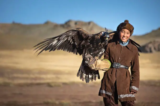 Traditional kazakh eagle hunter girl with his golden eagle that is used to hunt for fox and rabbit fur. Ulgii, Western Mongolia.
