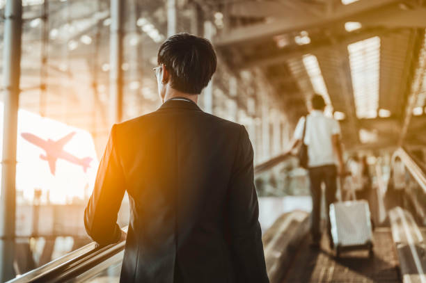 hombre de negocios que se traslada a la puerta de la terminal para el embarque con equipaje en el aeropuerto para viaje de negocios. - moving walkway fotografías e imágenes de stock