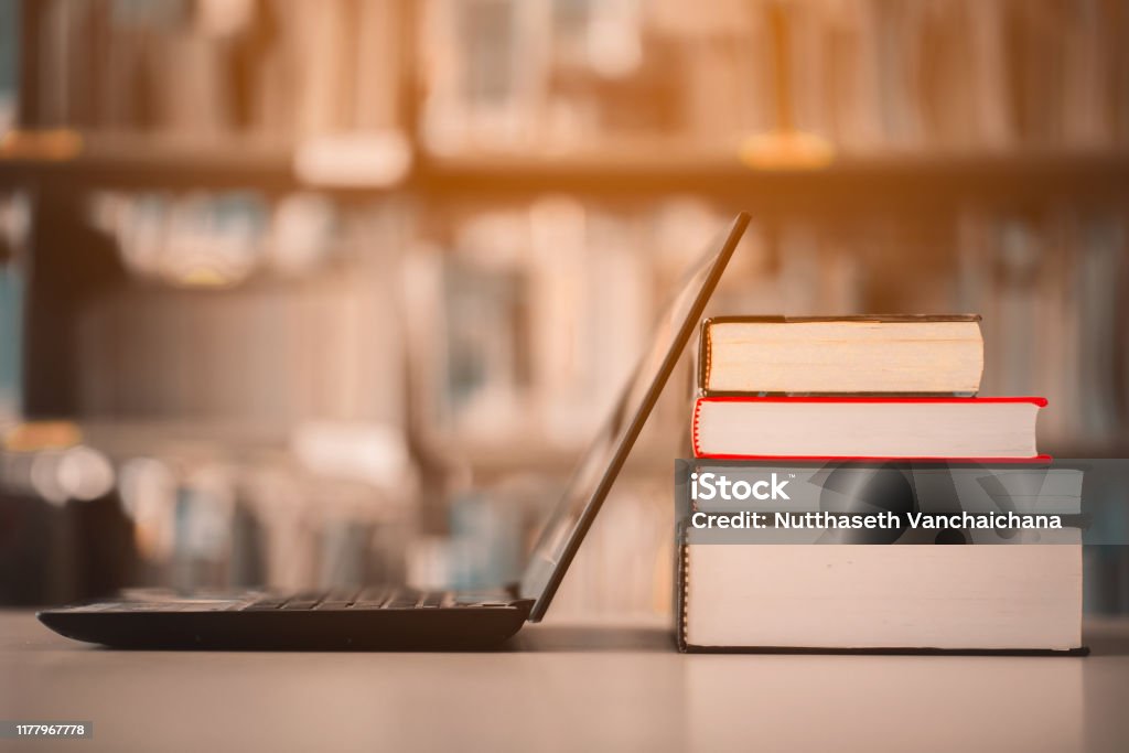 Bücherregale und Laptops befinden sich auf dem Schreibtisch der Bibliothek. E-Learning-Klasse und E-Book-Digitaltechnologie - Lizenzfrei Buch Stock-Foto