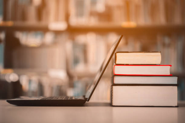 図書棚とノートパソコンは図書館のデスクに置かれています。e  ラーニングクラスと電子書籍デジタル技術 - 集める 写真 ストックフォトと画像