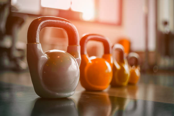 Woman in exercise gear standing in a row holding dumbbells during an exercise class at the gym.Fitness training with kettlebell in sport gym. stock photo