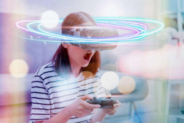 istock Concept connection and interfaces of digital technology, Excited young Asian woman using a virtual reality headset and joysticks, beautiful light with color lines. 1177971033