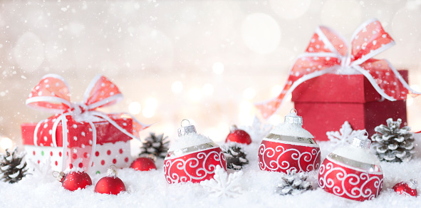 Glowing Christmas lantern and decor of fir tree branches and baubles in snow