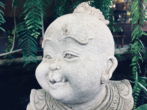 Laughing Buddha, ancient porcelain figurine in the garden