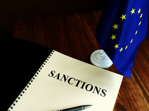 Lista de sanciones y bandera de la UE en el escritorio. photo