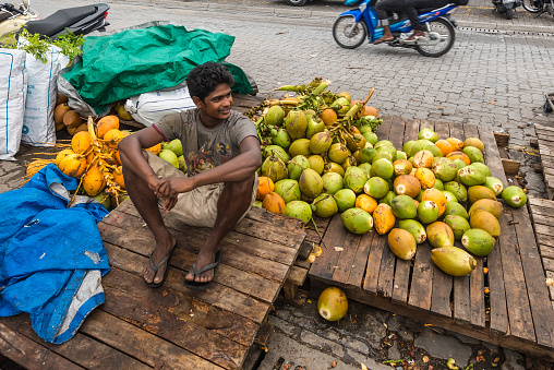 Male, Maldives - November 16, 2017: Vendor sells coconuts on the street in cloudy weather in Male, capital of Maldives. Male Local Market in Maldives.