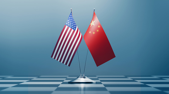 American and Chinese flag pair on a chess board. Horizontal composition with copy space and selective focus.