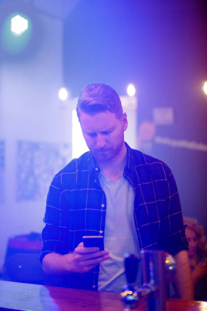 istock Young man with smart phone looking worried in the pub 1178009752