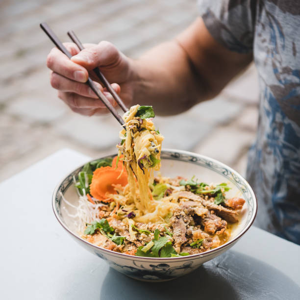 istock Man eating vietnamese noodle curry with chopsticks, square crop 1178010628