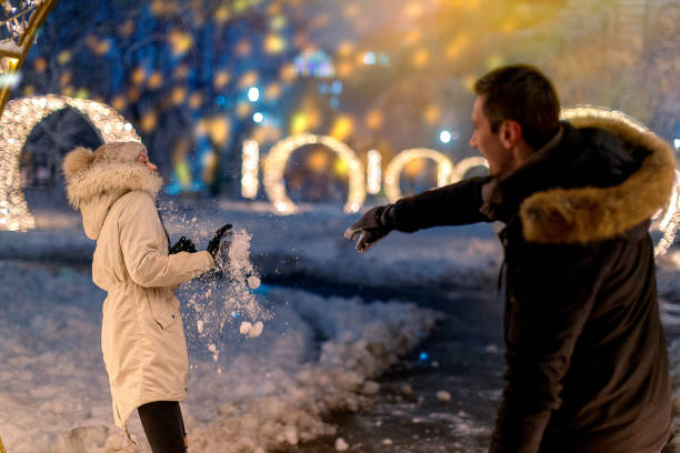 istock Young man throwing a snowball at his girlfriend 1178010758