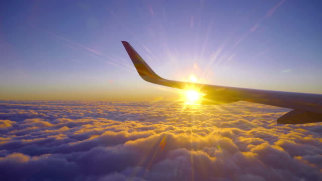 Beautiful Golden Sunset Sunrise Flight with Sun light Beam and Airplane Wing