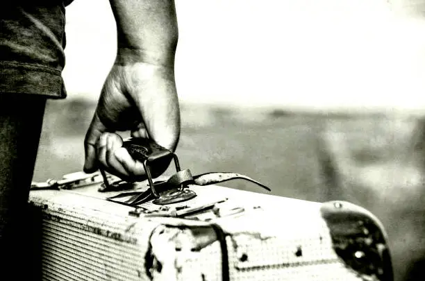 Refugee girl with her suitcase, close up BW