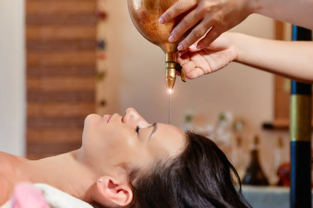 shirodhara, an ayurvedic healing technique. oil dripping on the female forehead. portrait of a young woman at an ayurvedic massage session with aromatic oil dripping on her forehead and hair - ayurveda massaging aromatherapy chakra imagens e fotografias de stock