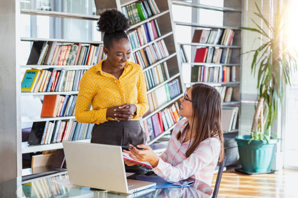 istock Working team is talking at desk with laptop in modern office. Two people discussing information seen on screen of silvery device and smiling friendly. Prospective staff dressed in formal clothes 1178017735
