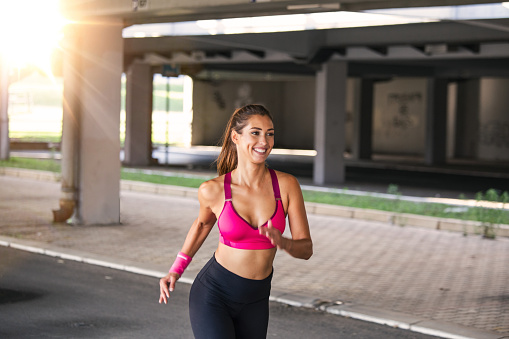 Young woman with fit body running Female model in sportswear exercising outdoors.Woman Doing Workout Exercises On Street.