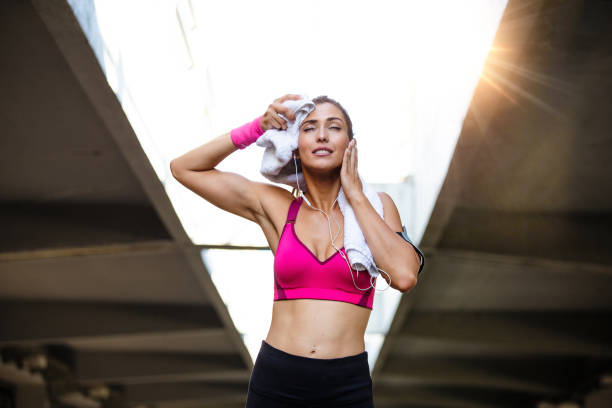 istock Young smiling female resting after an active fitness training while standing against gray wall with copy space area for your text message, satisfied fit woman resting after an active fitness training 1178019338