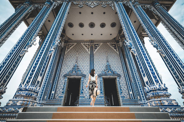Young tourist woman enjoying her day in the famous Wat Pho Buddhist temple in Bangkok, Thailand. She is walking on a nice, sunny day, contemplating, enjoying the rich history of the famous place.