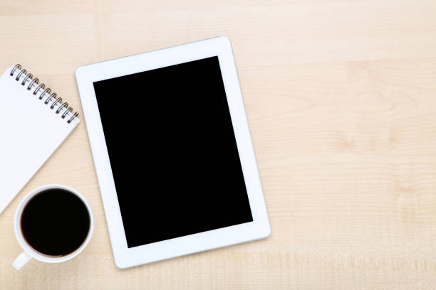 istock Tablet computer with notepad and cup of coffee on wooden table 1178019566