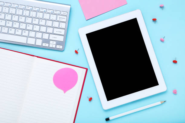 istock Tablet and computer keyboard with office supplies on blue background 1178019825