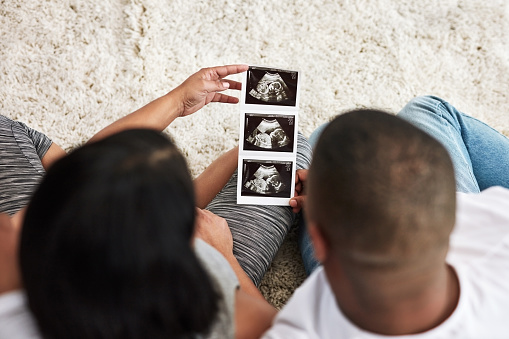 Rearview shot of a couple looking at a sonogram of their unborn baby