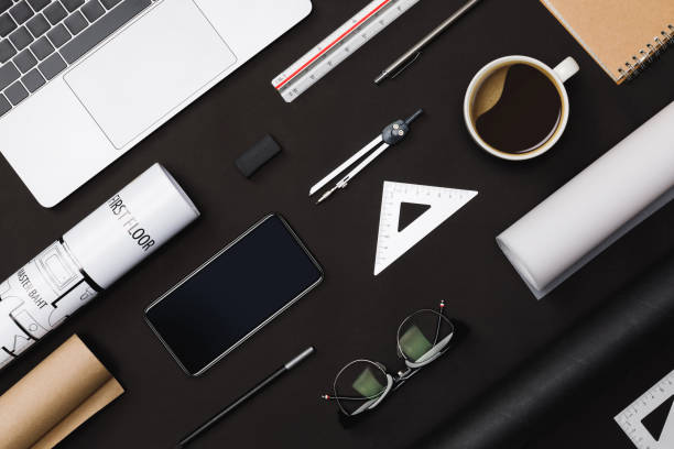 istock Creative flat lay of architects black table with roll blueprints, architectural project plan, engineering tools, office supplies, laptop computer and a cup of hot coffee,Workspace for designer concept 1178028908