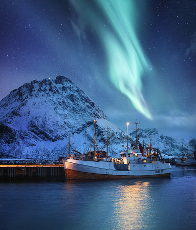 Aurora Borealis, Lofoten islands, Norway. Nothen light, mountains and boat. Winter landscape at the night time. Norway travel - image