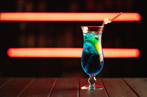 Fresh blue cocktail on a neon background. Alcoholic cocktail. Fruit Non-alcoholic cocktail.
