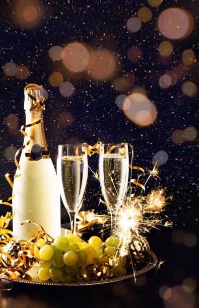 New year celebration with grapes and champagne A bottle of champagne, two glasses, grapes and ornaments on a tray to celebrate the New Year champagne grapes stock pictures, royalty-free photos & images