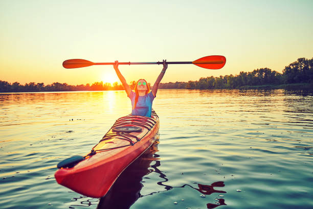 le persone kayak durante il tramonto sullo sfondo. divertiti nel tuo tempo libero. - lake summer beach nautical vessel foto e immagini stock