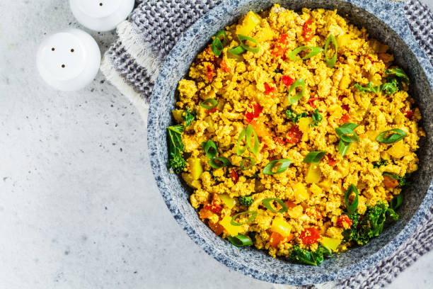 Tofu scramble with vegetables in a pan. Vegan Alternative Omelet.